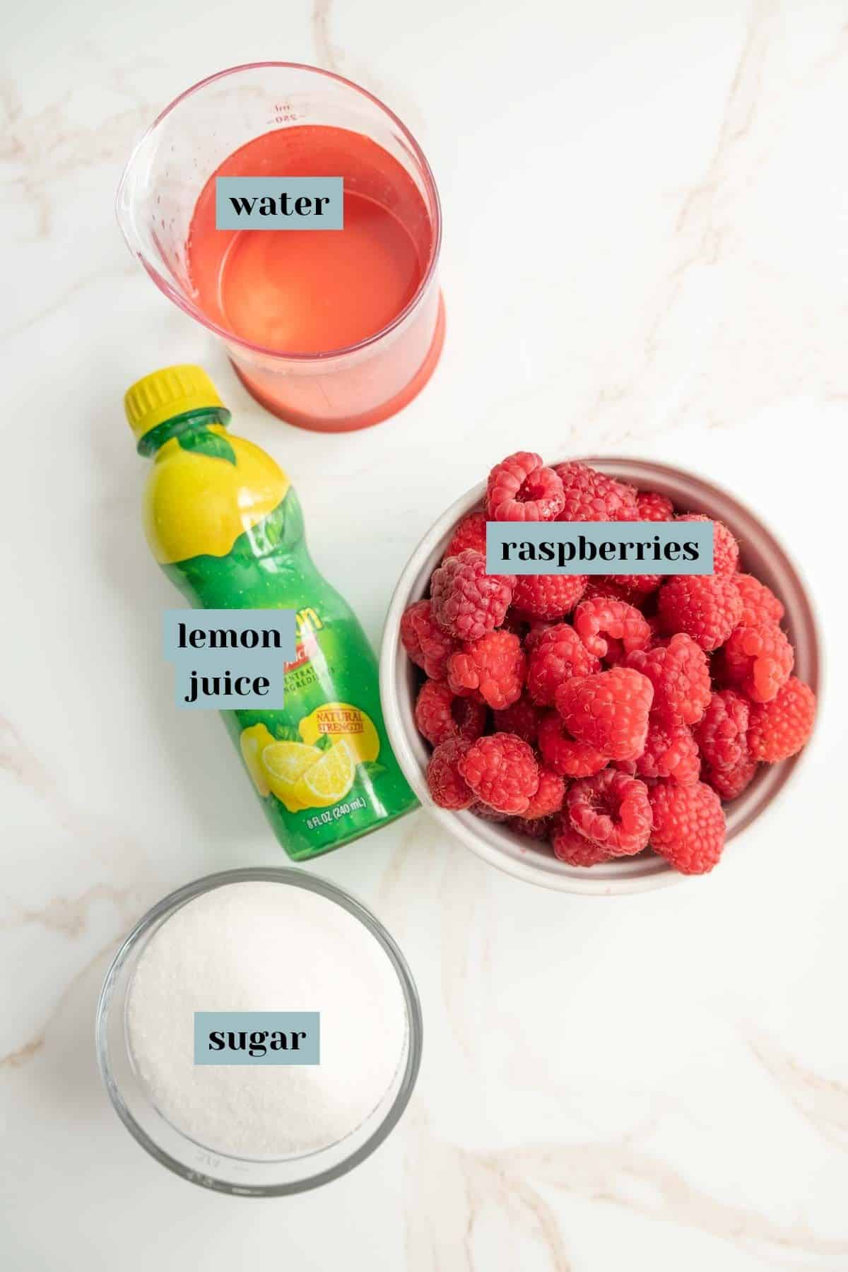 Ingredients for raspberry syrup: a bowl of raspberries, a measuring cup of water, a bottle of lemon juice, and a bowl of sugar.