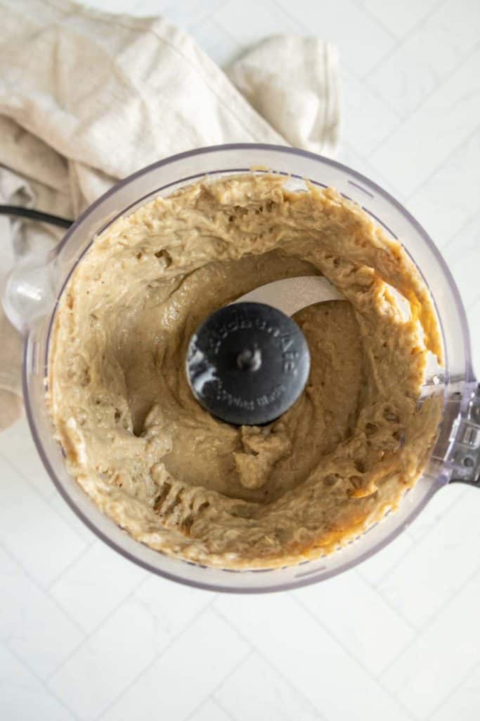 A food processor containing smooth, creamy eggplant dip.