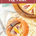 A slice of fig cake on an orange plate with a fork, positioned besides the remaining cake on a wooden plate. The text "fresh fig cake" is displayed at the top.