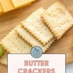 A wooden board with three rectangular butter crackers surrounded by slices of cheese. Text on the image reads: "Butter Crackers - snack time favorite. Get the recipe at stetted.com.