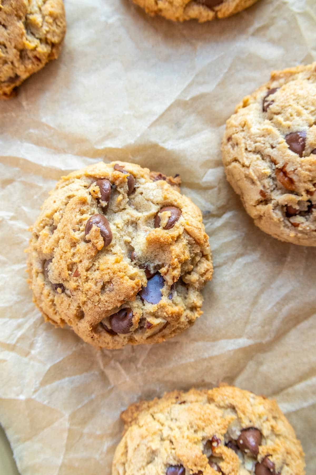 Three chocolate chip cookies on parchment paper.