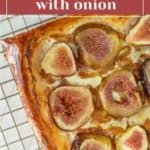 Close-up of a savory fig tart with caramelized onions, displayed on a cooling rack. The golden-brown crust cradles slices of fresh figs perfectly. Text at the top reads "Savory fig tart with onion.