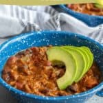 A bowl of pumpkin turkey chili topped with avocado slices. The text reads "pumpkin turkey chili" and "easy slow cooker recipe" with a website link at the bottom.