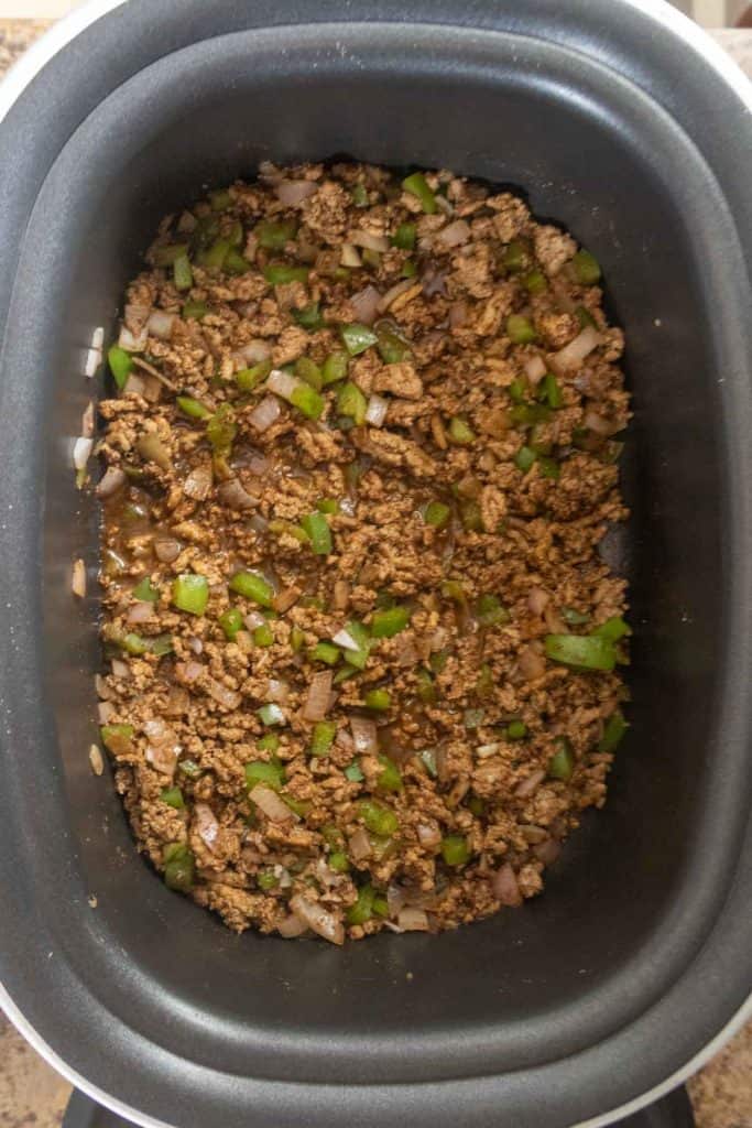 Ground meat cooked with chopped green bell peppers and onions in a slow cooker.