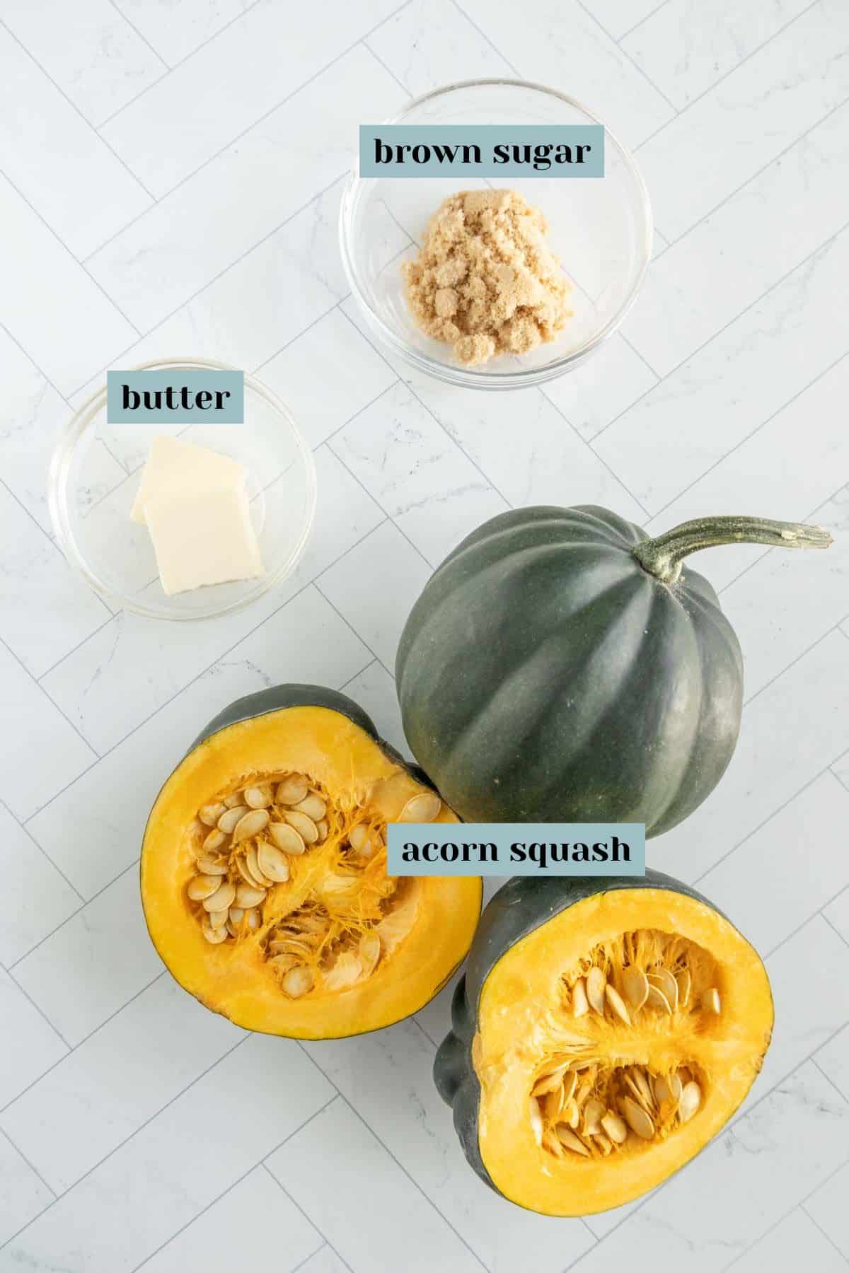 Image of ingredients including brown sugar and butter in separate bowls, and an acorn squash that is whole and halved, placed on a tiled surface.