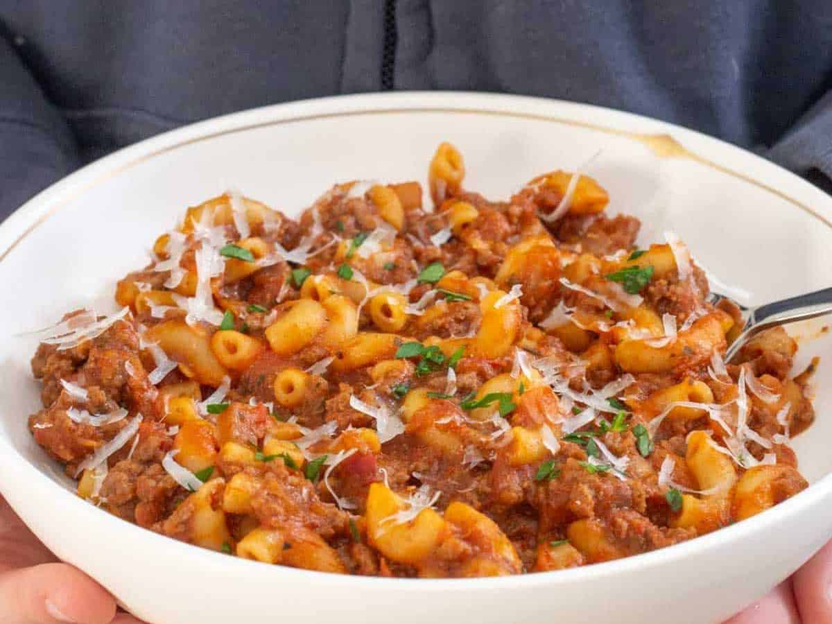 hands holding bowl of American goulash