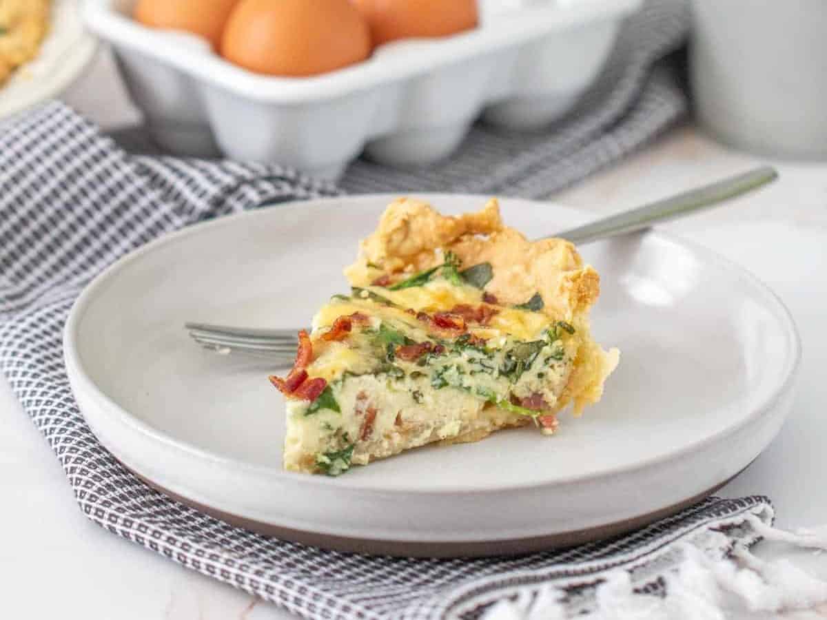 slice of bacon spinach quiche on a gray plate