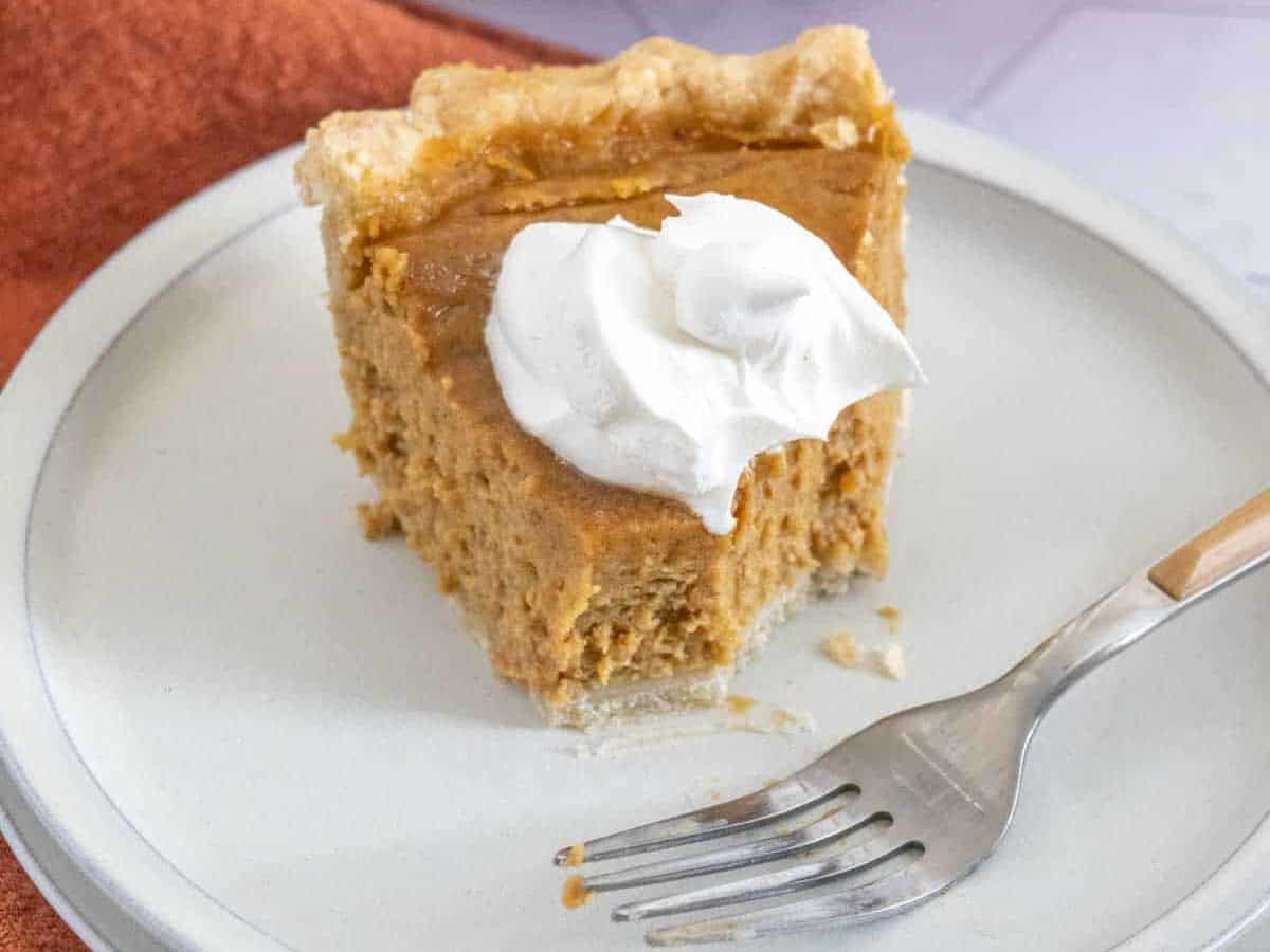 slice of butternut squash pie with whipped cream, half eaten