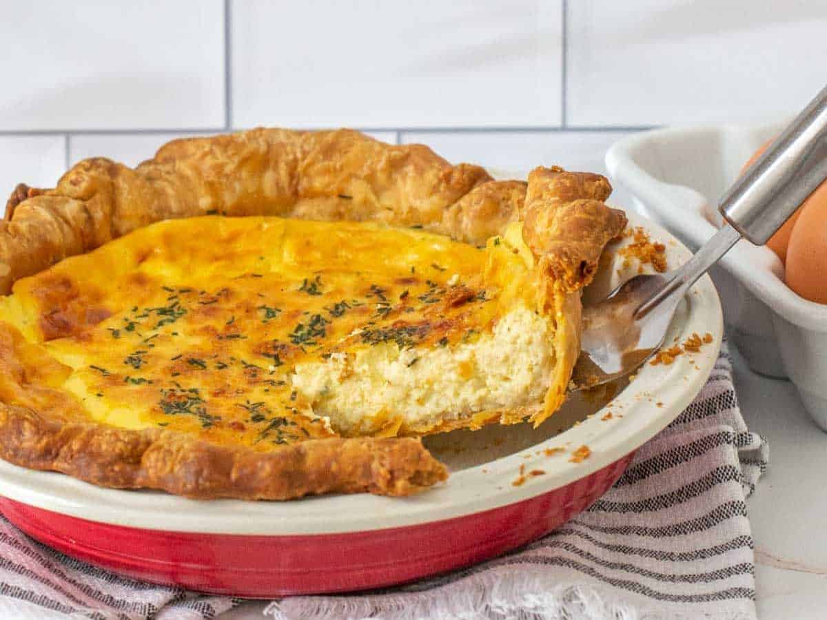 slice of cheese quiche being lifted from pie plate