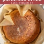 Round loaf of rosemary parmesan bread in a parchment-lined Dutch oven.