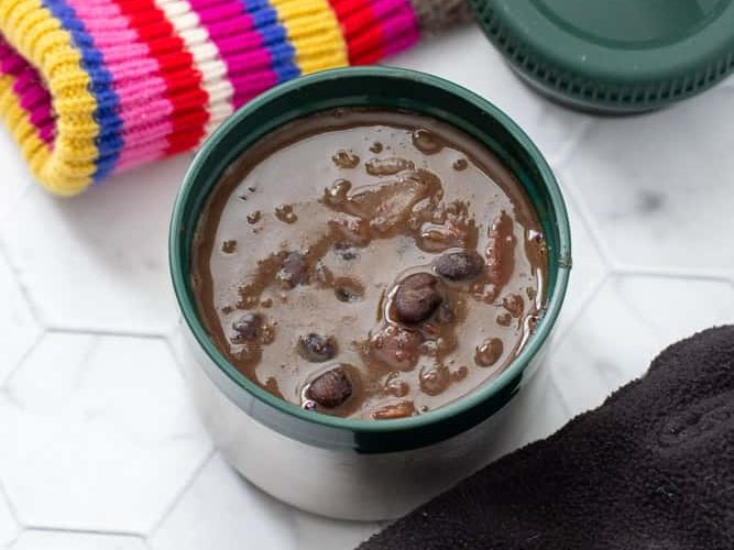 black bean soup in stanley food jar overhead, with winter gear beside