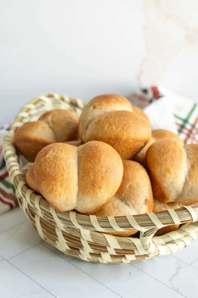 A basket filled with freshly baked dinner rolls on a countertop.