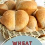 A basket filled with wheat dinner rolls on a table, with text at the bottom reading "Wheat Dinner Rolls.