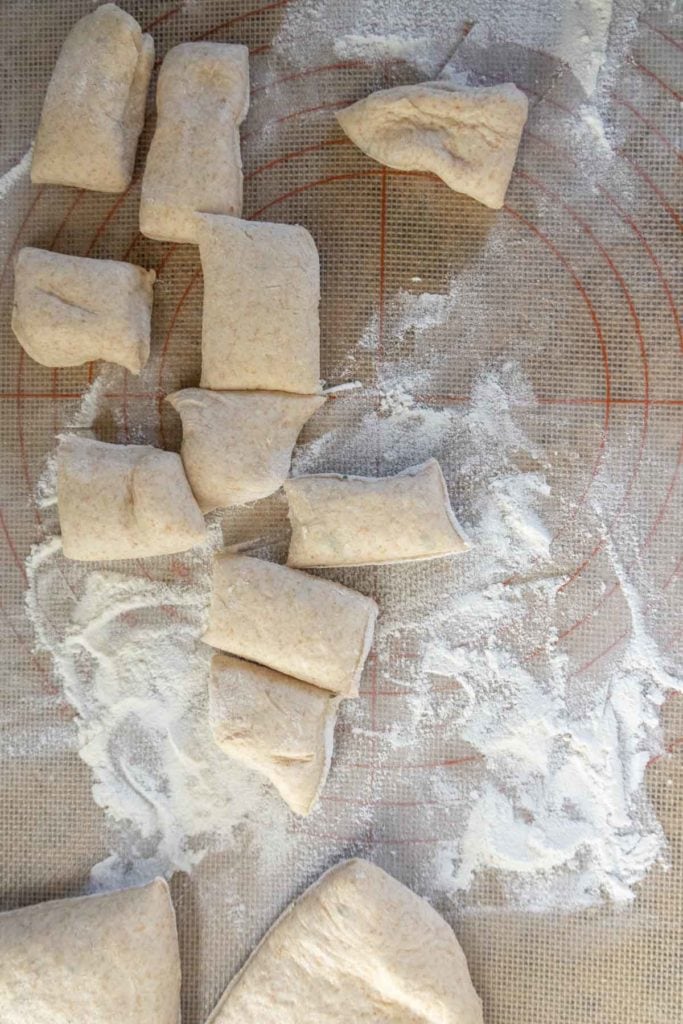 Dough pieces on a floured surface arranged on a silicone mat with a circular measurement guide.