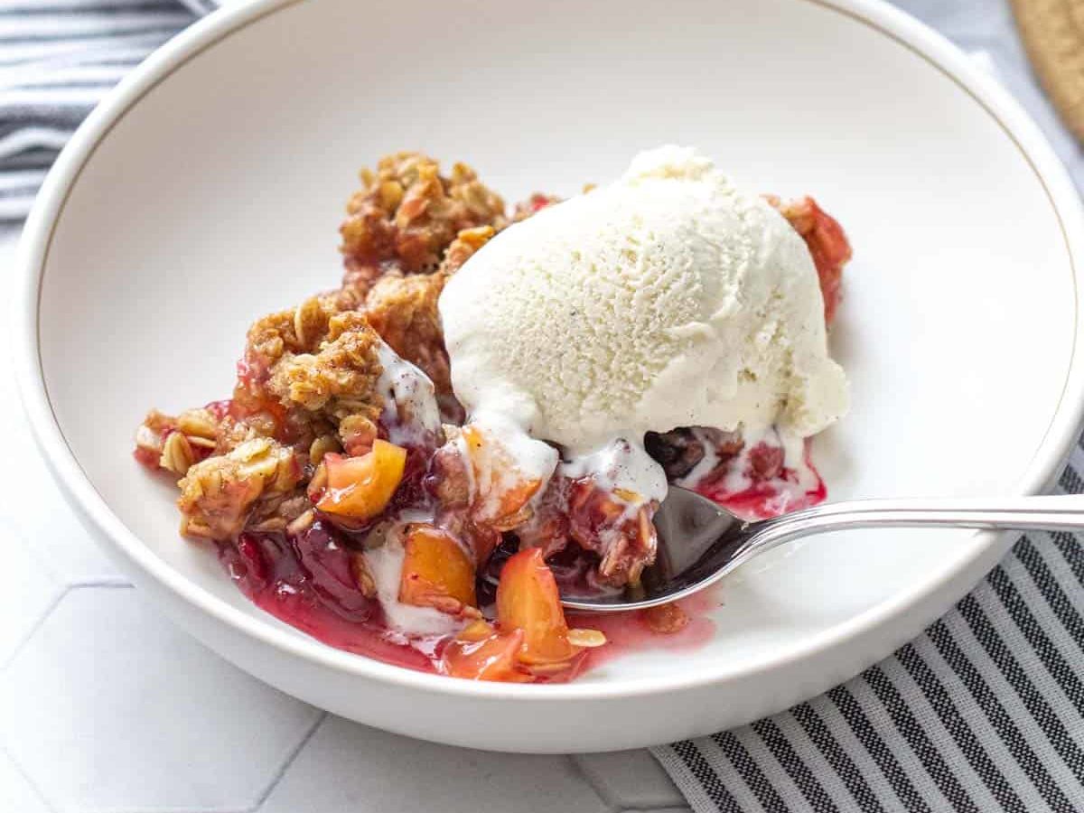 bowl of apple cranberry crisp with vanilla ice cream