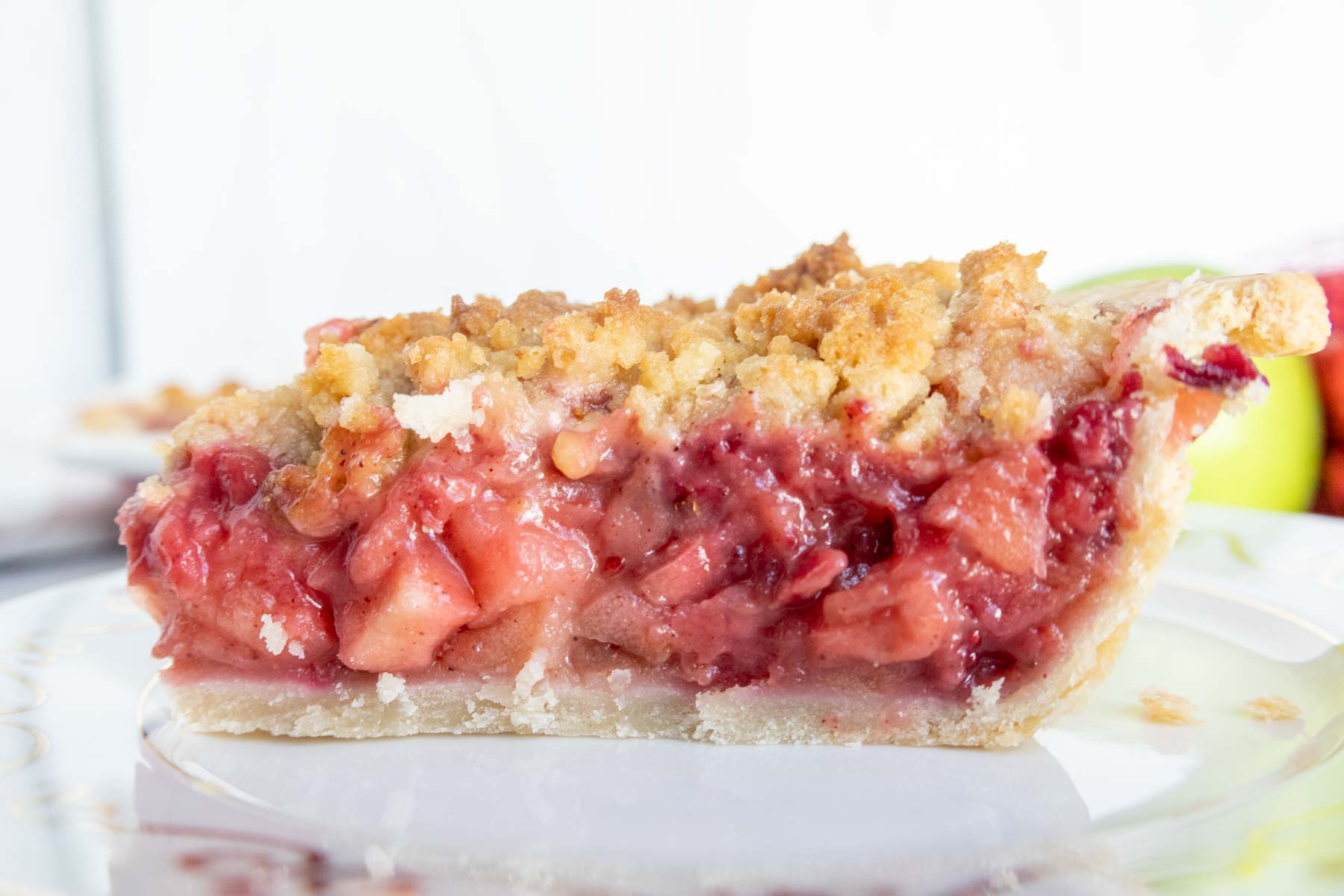 A slice of fruit pie with a crumbly topping on a white plate.