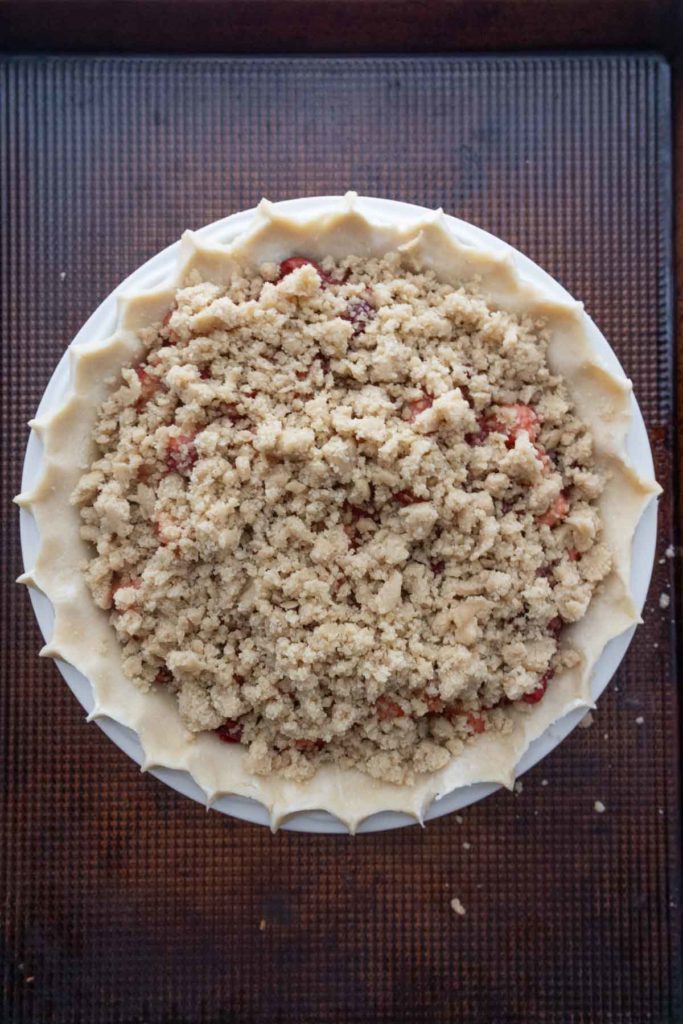 A pie with a crumbly topping sits on a baking sheet.