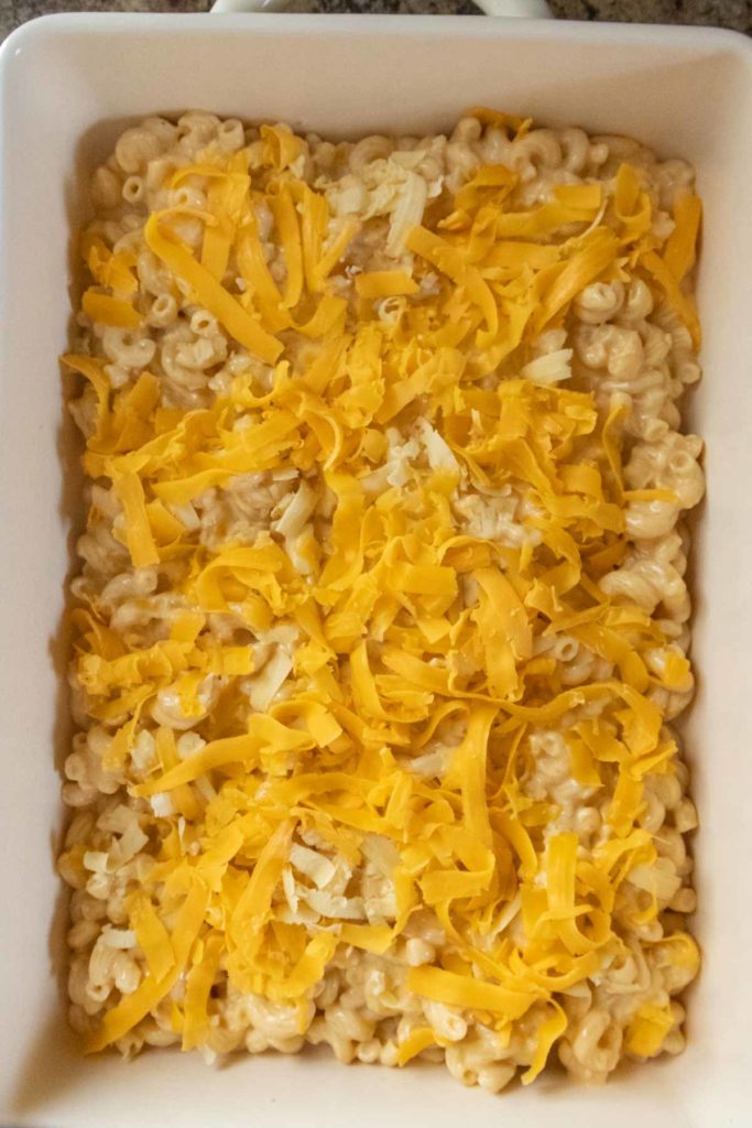 A rectangular dish filled with macaroni and cheese, topped with shredded cheddar cheese.