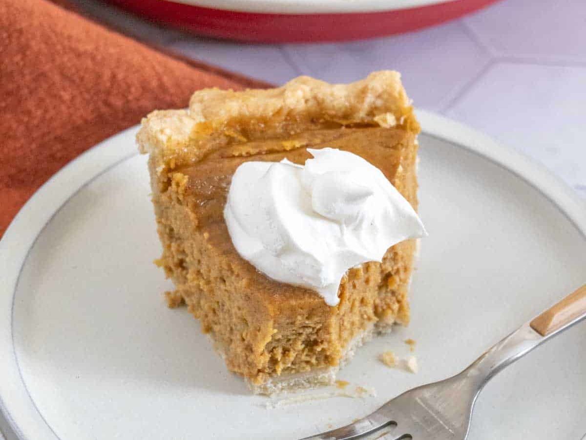 slice of butternut squash pie with whipped cream, half eaten