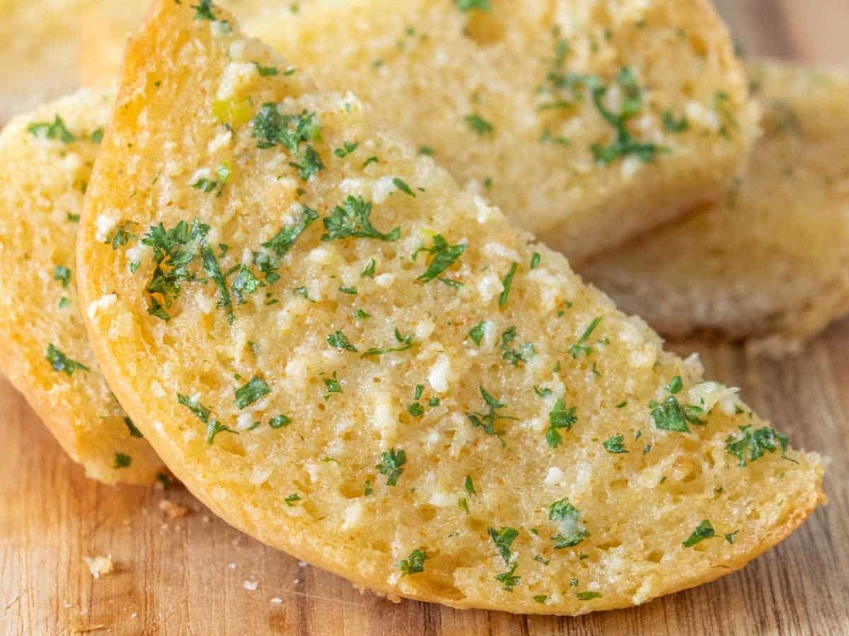 Sliced garlic bread close up on a wooden cutting board.