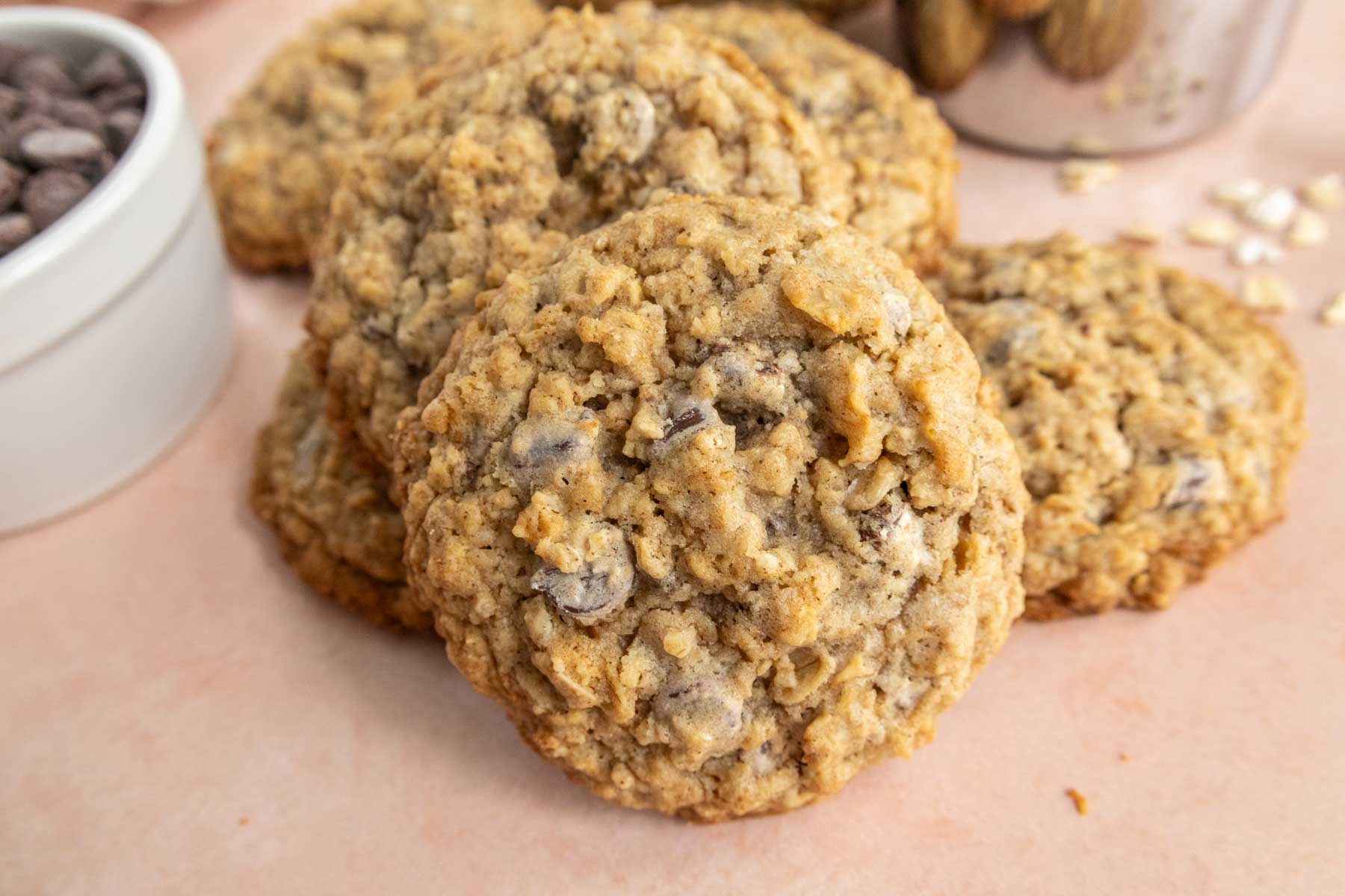 Oatmeal cookies with chocolate chips stacked on a light surface.