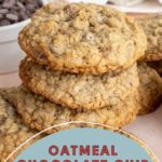 Stack of oatmeal chocolate chip cookies with a bowl of chocolate chips in the background.