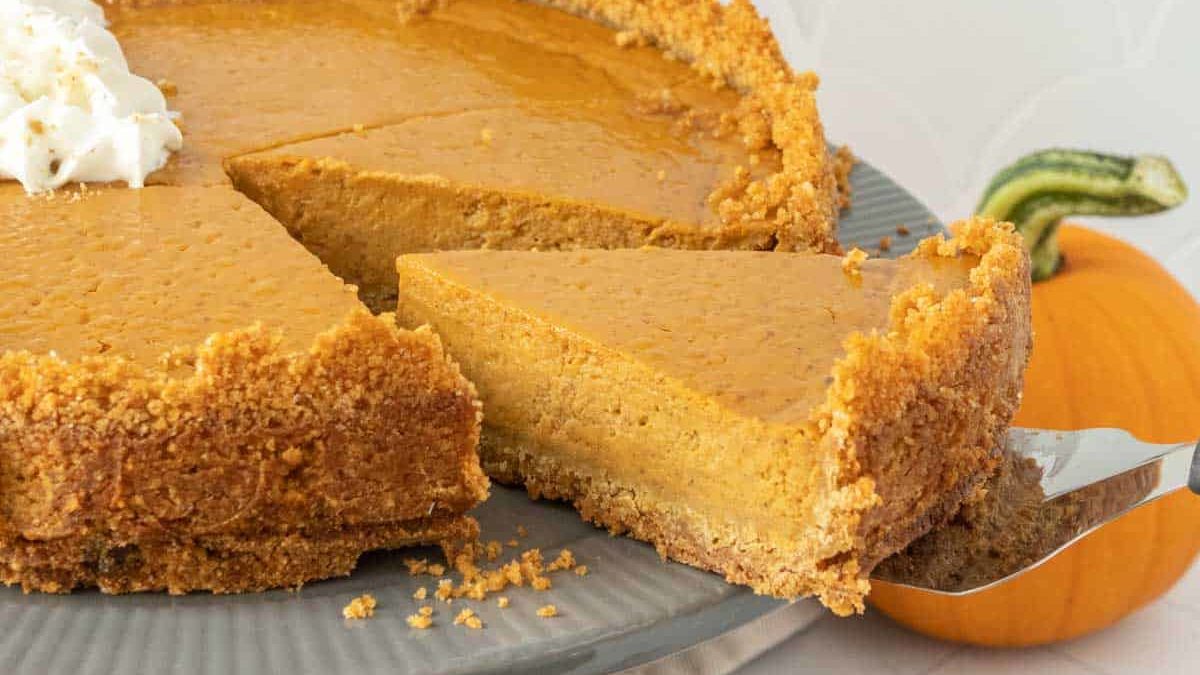 Pumpkin pie on a plate with a slice taken out.