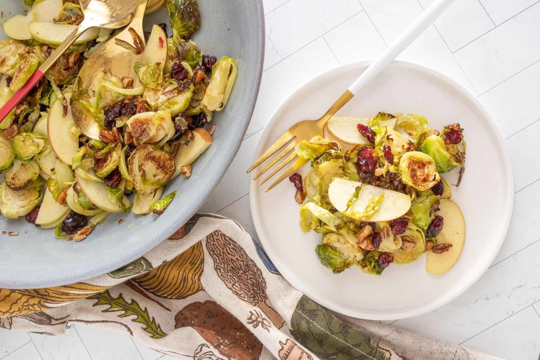 A plate of brussels sprouts with apples and cranberries.