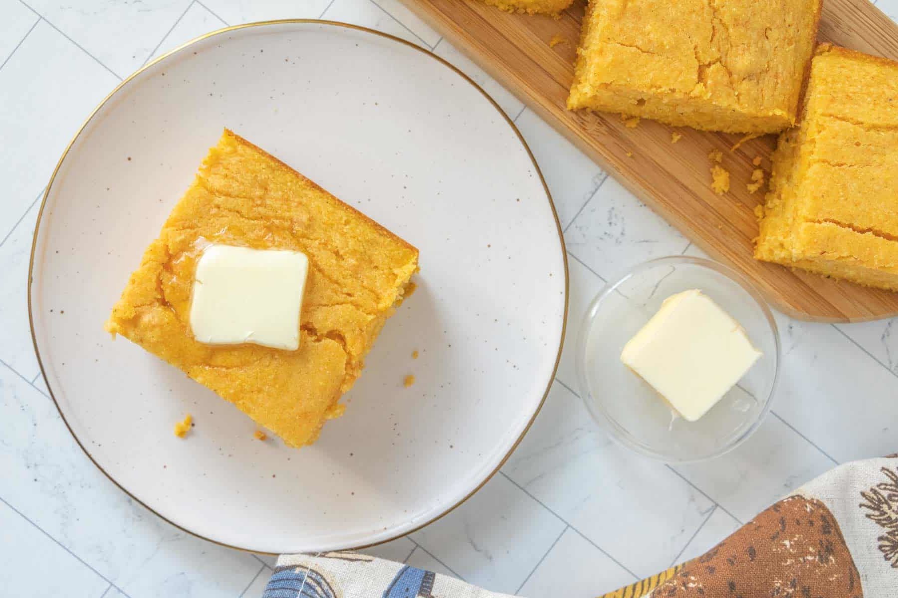 Cornbread with butter on a plate.