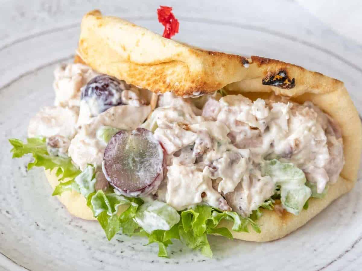 Chicken salad with grapes in a folded over flatbread on a gray plate.