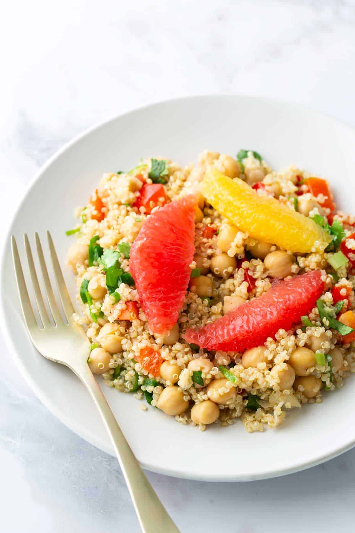 A bowl of quinoa salad topped with fresh grapefruit and orange segments.