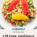 A plate of citrus quinoa salad with chickpeas, red and yellow grapefruit slices, and chopped vegetables.