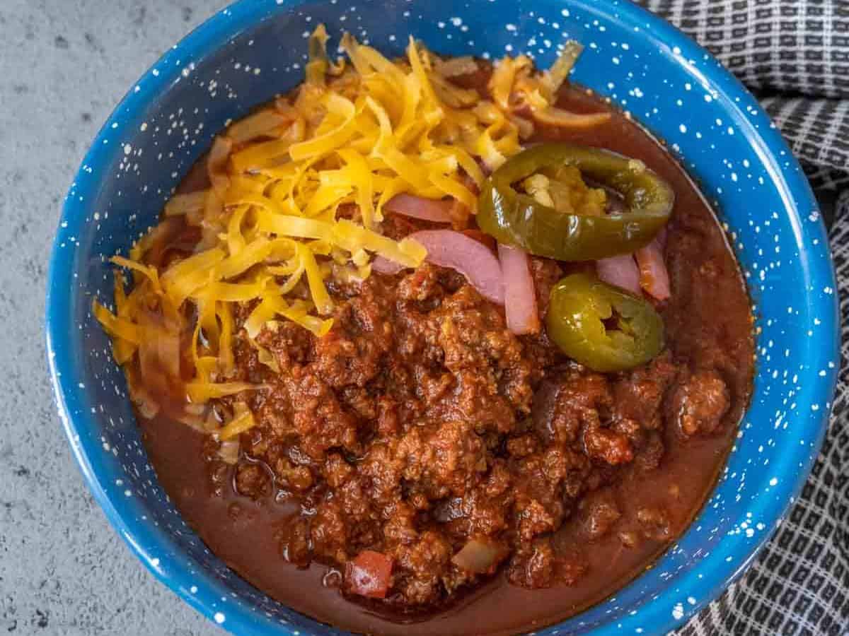 Bowl of bison chili with shredded cheese and jalapeños on top.