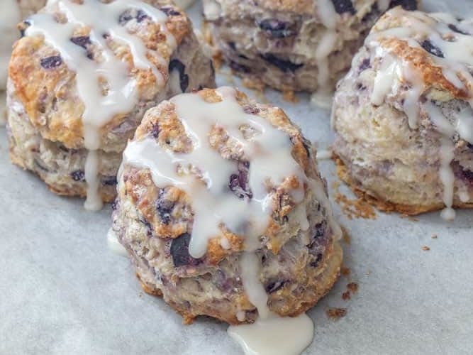 baked blueberry biscuits with icing on a baking sheet