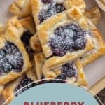 A tray of blueberry Danish pastries dusted with powdered sugar.