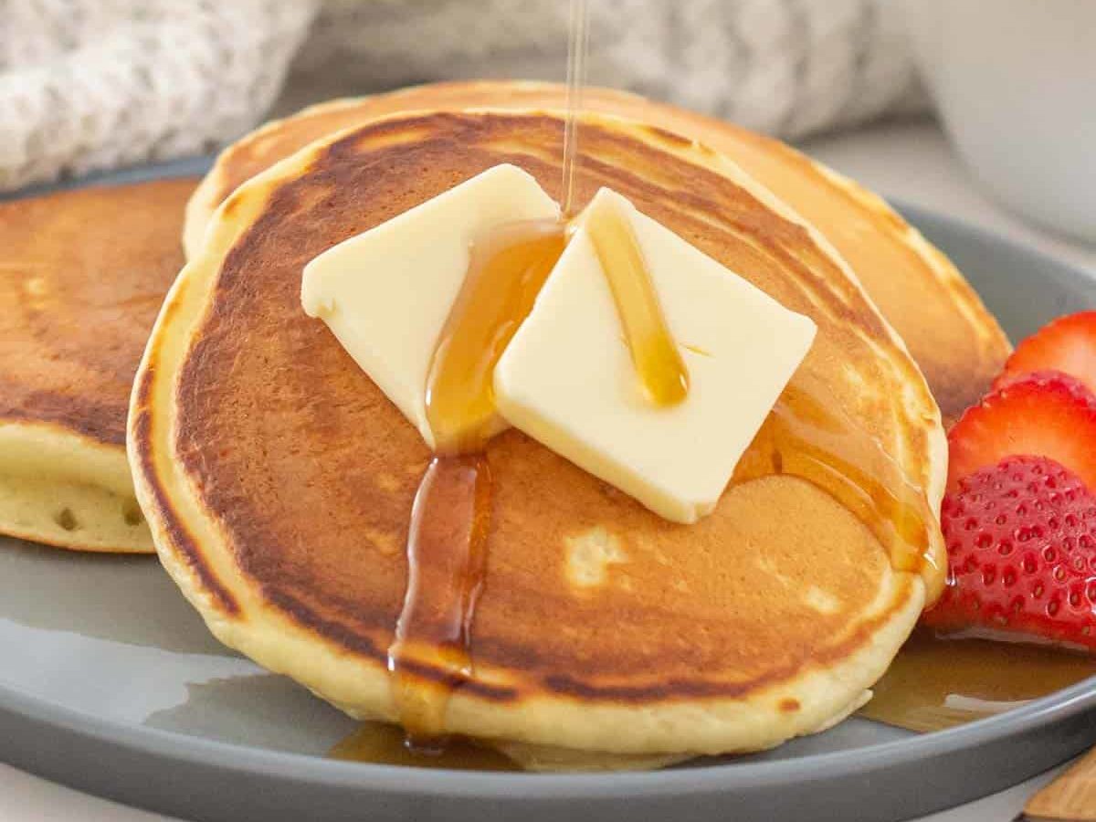 maple syrup being poured onto buttermilk pancakes