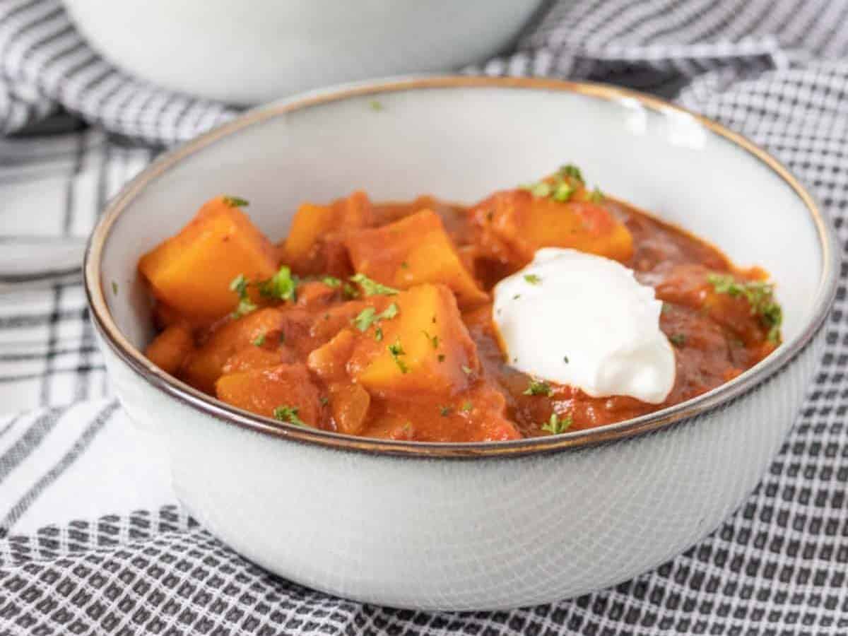 Bowls of butternut squash chili on black and white napkins.