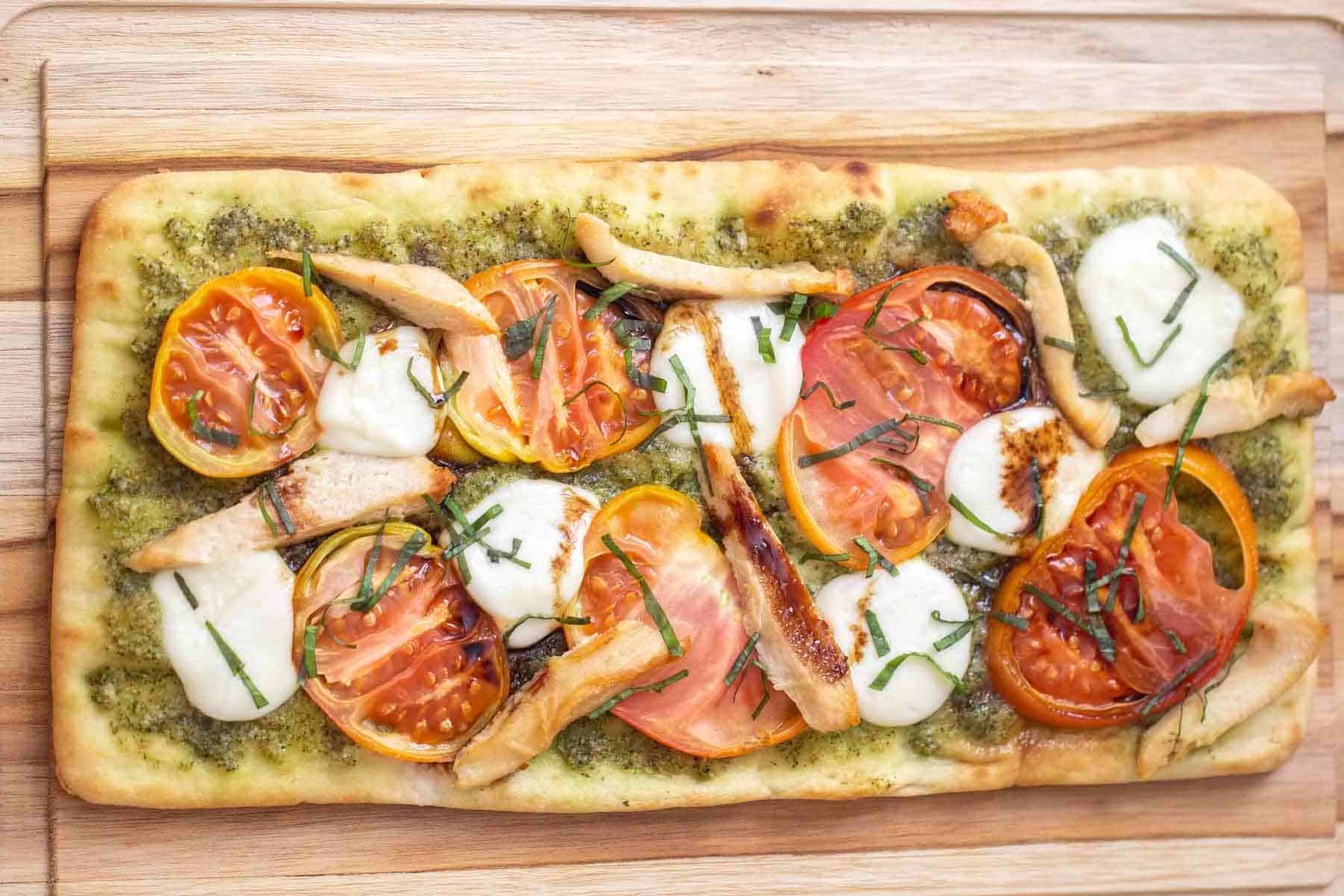 overhead caprese flatbread with chicken on cutting board