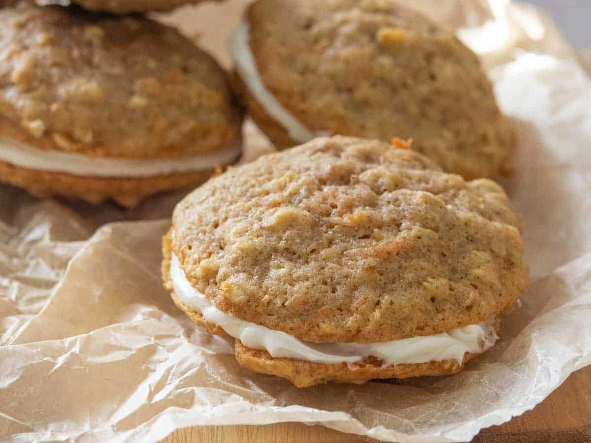 Carrot cake cookies with cream cheese frosting on a sheet of parchment paper.