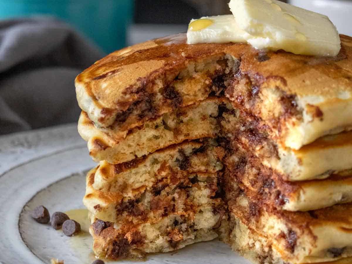 Stack of chocolate chip pancakes with a wedge cut out so the interior is seen.