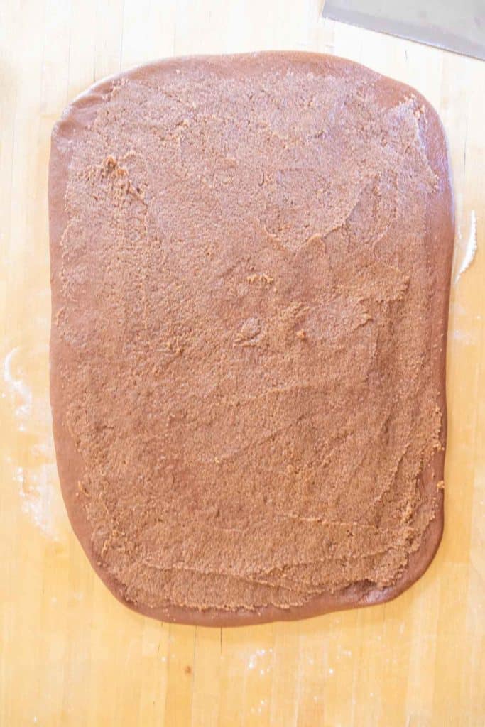 A sheet of rolled-out brown dough on a wooden surface, ready for baking.