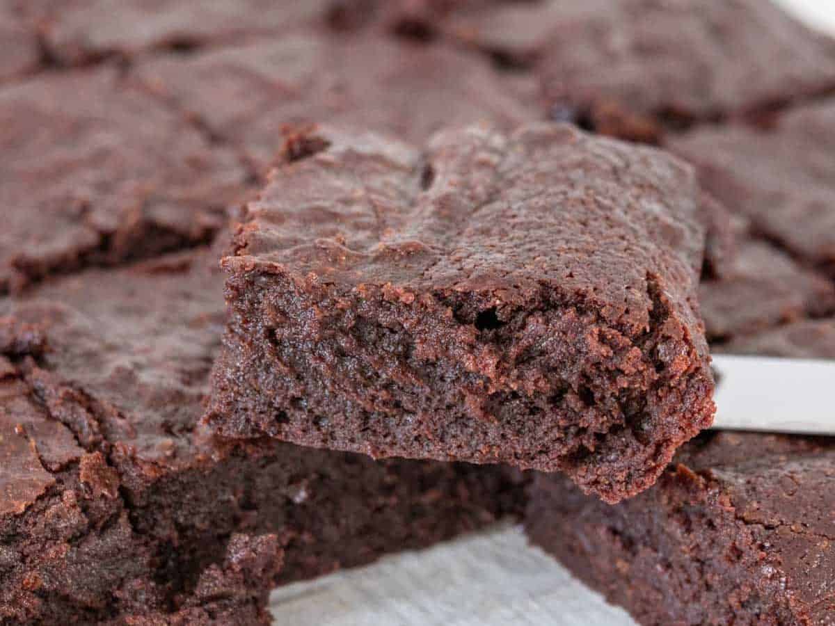 Sliced fudgy brownies on a cooling rack with one stacked on top.