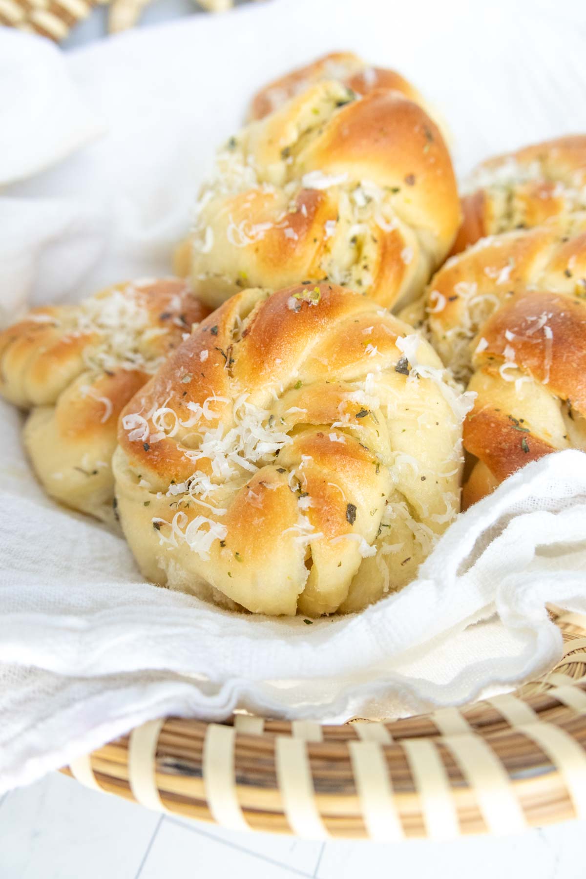 Basket of freshly baked garlic knots topped with grated cheese.