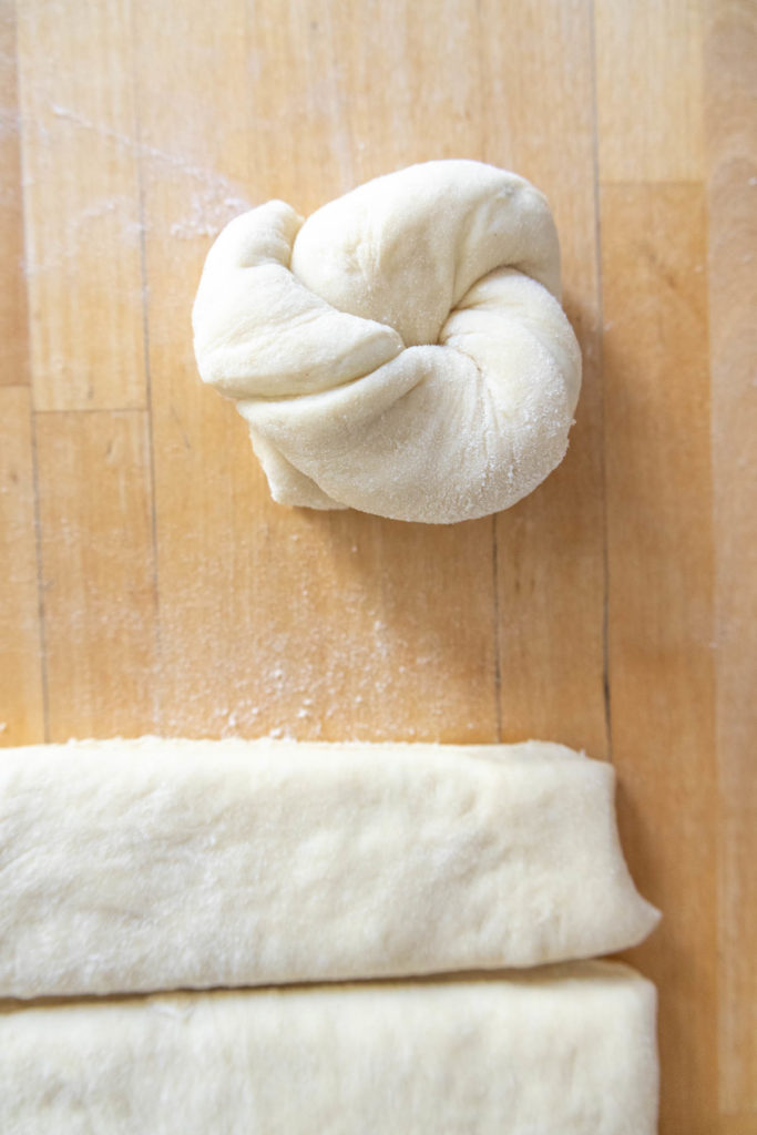 Dough ball and flat dough strips on a wooden surface.