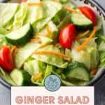 A salad with lettuce, cucumber slices, cherry tomatoes, and shredded carrots in a bowl. A sign reads, "Ginger Salad Dressing. Get the recipe at Stetted.com.