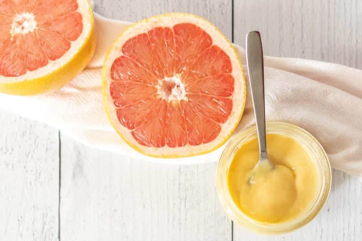 Grapefruit curd in a jar with cut grapefruit beside.