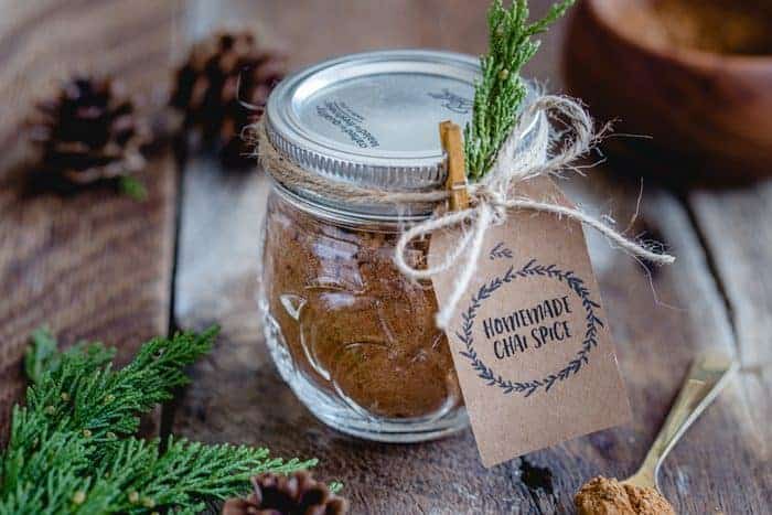 A glass jar filled with chai spice mix and a homemade tag tied on it.