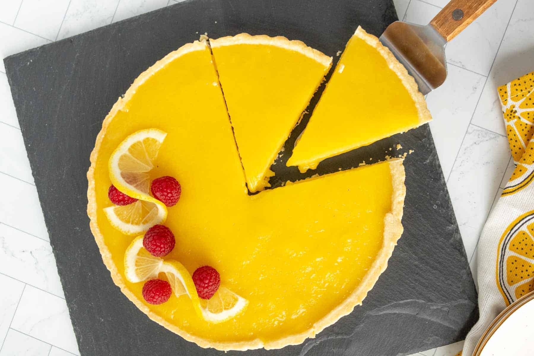 A lemon tart with a slice taken out of it.