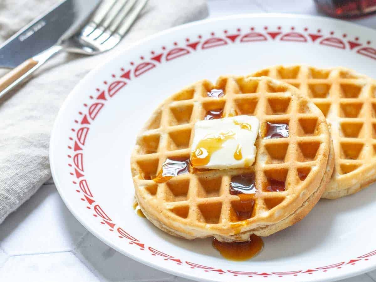 plate of peanut butter waffles with butter and syrup