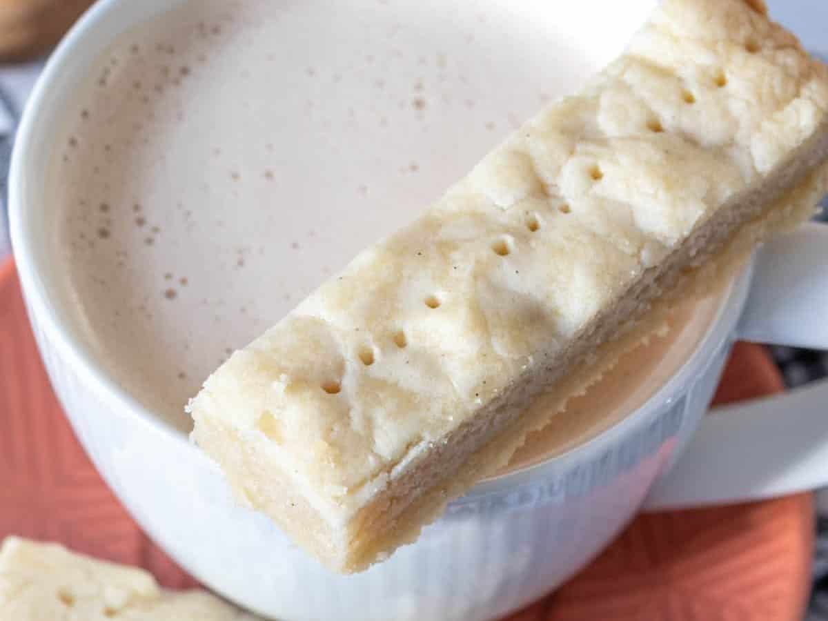 Sliced shortbread cookie resting on a cup of chai.